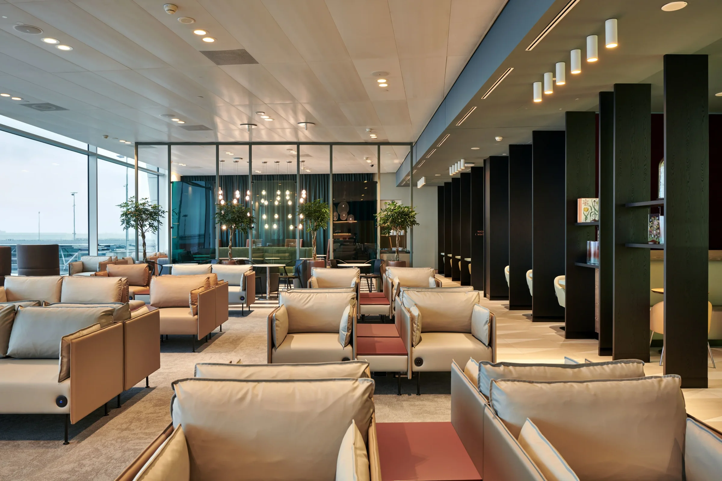 Helle Sessel vor der Glasfront mit Blick aufs Vorfeld in der Aspire Lounge 41 am Flughafen Amsterdam Schiphol